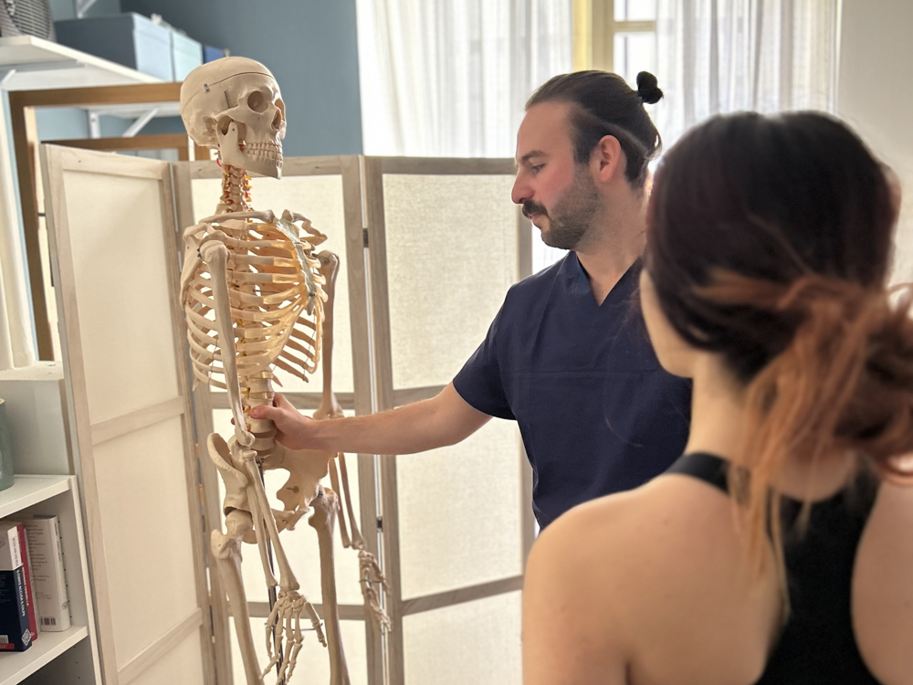 Kevin Zalateu (ostepata torino) spiega ad una paziente l osteopatia utilizzando uno scheletro
